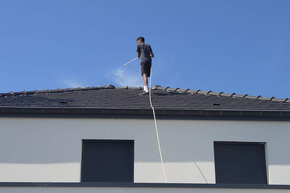 Application du traitement démoussant à la perche, depuis le faîtage