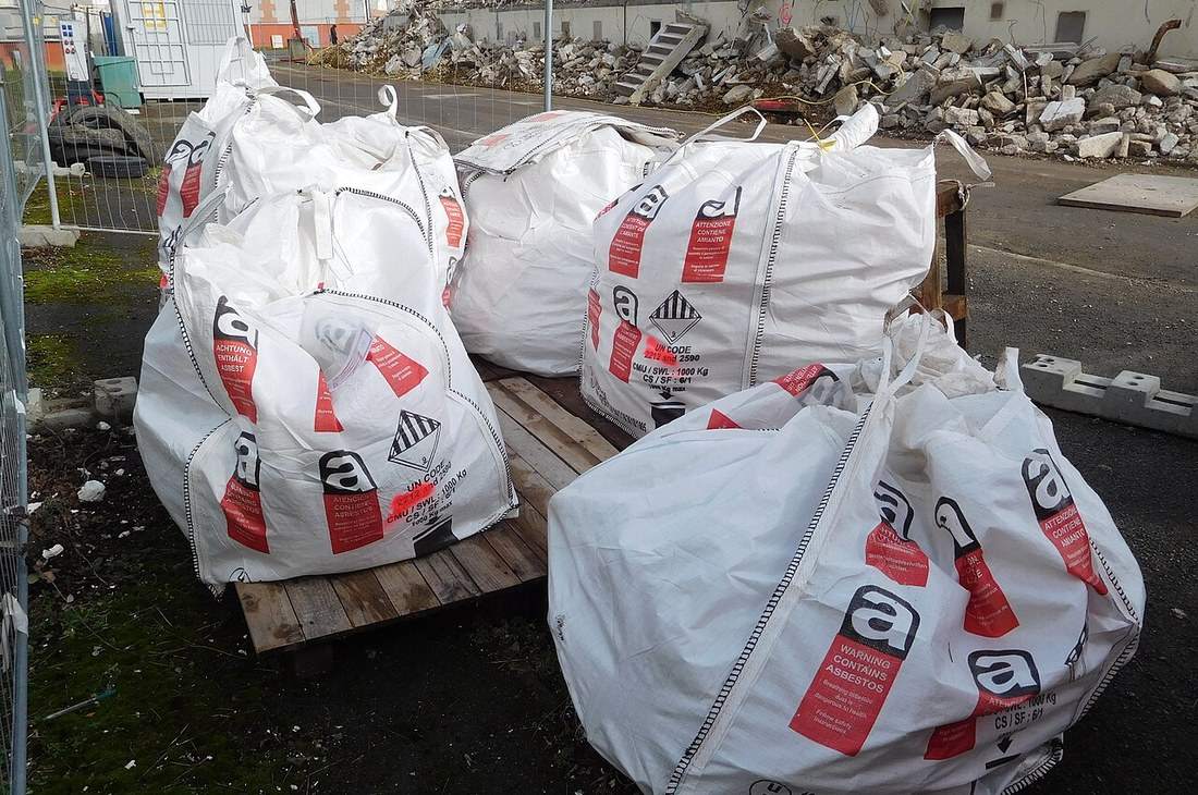 Big-bags de déchets amiantés fermés et étiquetés, posés sur des palettes avant enlèvement
