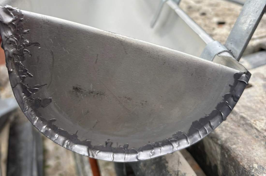 Bout de gouttière en zinc soudé, posé sur l'échafaudage du chantier