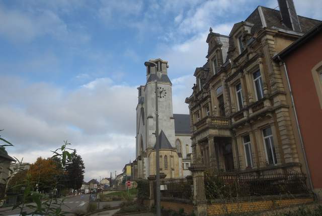 Rue d'Audun-le-Tiche avec l'église en fond et une maison de maître en pierre