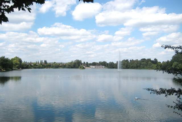 Étang de la Ballastière à Hagondange, plan d'eau et jet d'eau sous un ciel de nuages