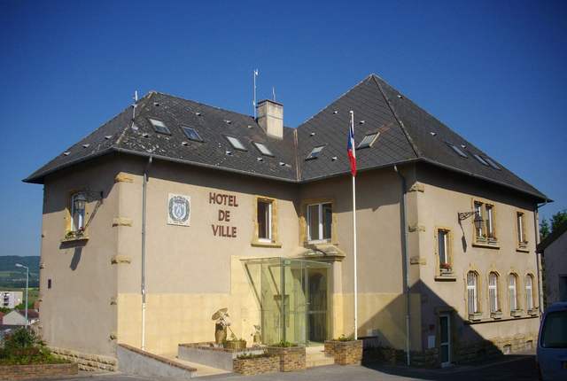 Mairie de Hettange-Grande, façade claire à toit d'ardoise et drapeaux