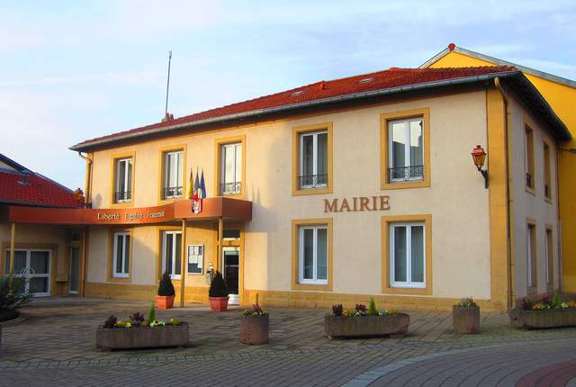 Mairie d'Illange, façade jaune et volets, drapeaux à l'entrée