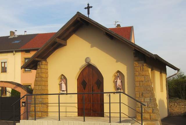 Chapelle d'Illange, petit édifice en pierre à porte cintrée et statues