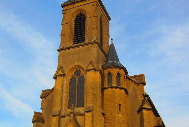 Église de Kuntzig, façade en pierre ocre et flèche d'ardoise