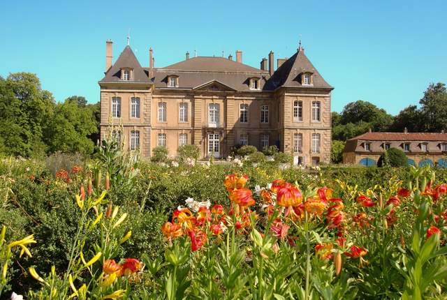 Château de La Grange à Manom, façade en pierre derrière un massif de fleurs