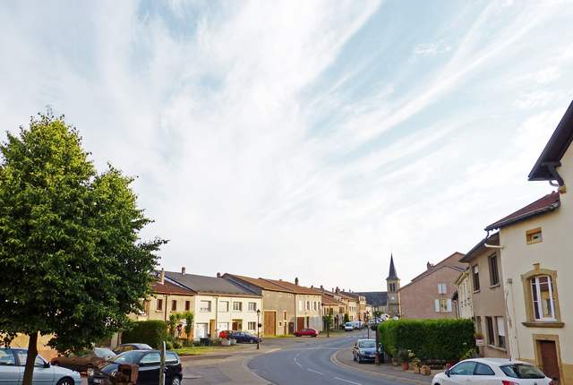 Rue de la Gare à Metzervisse, maisons de village et clocher au fond