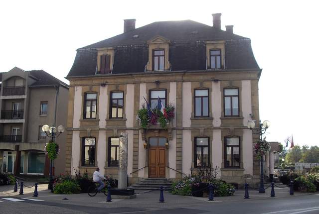 Hôtel de ville d'Uckange, façade en pierre à toit mansardé et fleurs