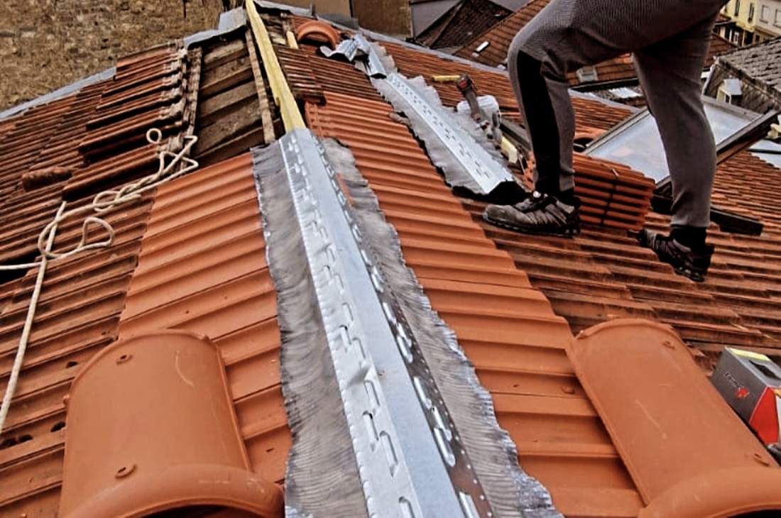Faîtage en cours de réfection : closoir ventilé fixé sur la ligne de faîte, faîtières en terre cuite prêtes à poser