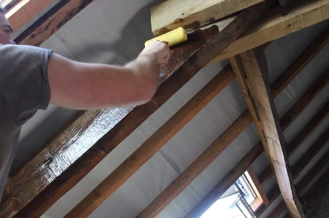 Application au rouleau d'un produit de protection sur une panne de charpente, dans un comble