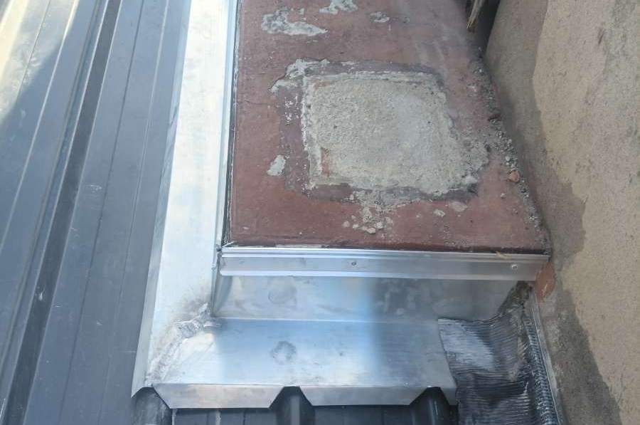 Solin en zinc neuf au raccord entre une couverture en bac acier et un muret maçonné