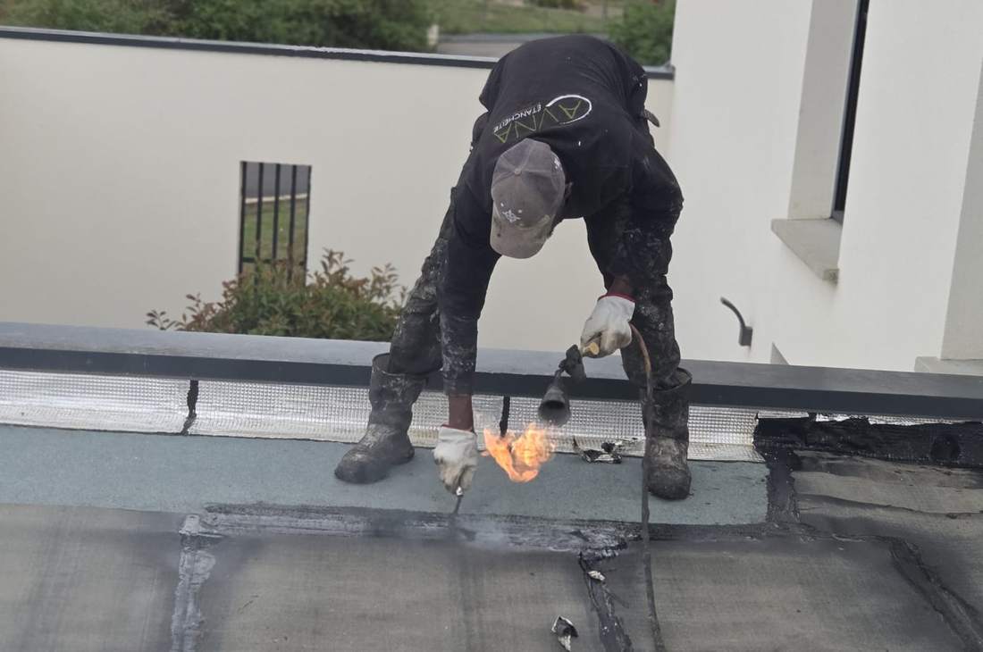 Couvreur soudant une membrane d'étanchéité au chalumeau sur un toit plat