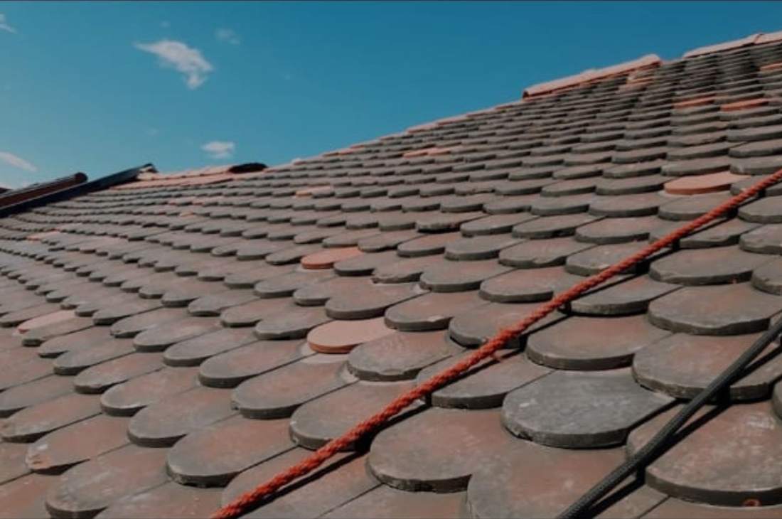 Toiture en tuiles plates anciennes avec faîtage rouge